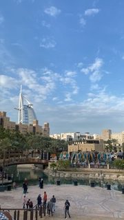 Dubai waterfront walkway, sailboat skyscraper beyond